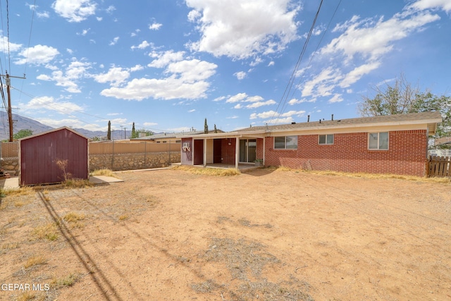 back of property featuring a storage unit, an outdoor structure, fence, and brick siding