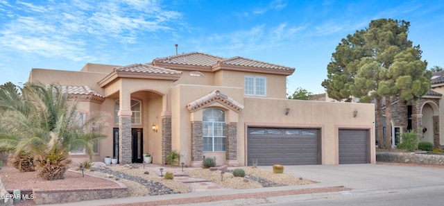 view of front of house with stucco siding, driveway, a tiled roof, stone siding, and a garage