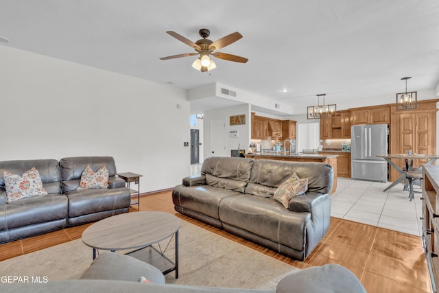 living area with a ceiling fan, a chandelier, and light tile patterned floors