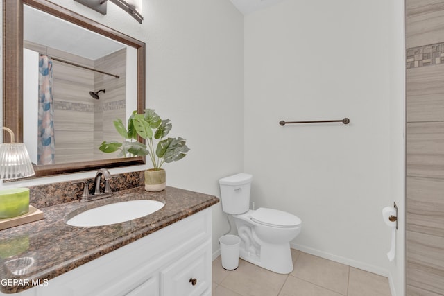 bathroom featuring tile patterned flooring, a tile shower, vanity, toilet, and baseboards