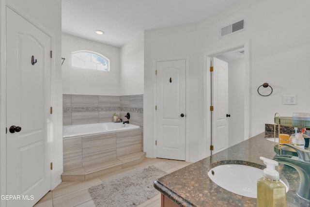 bathroom featuring a garden tub, vanity, and tile patterned flooring
