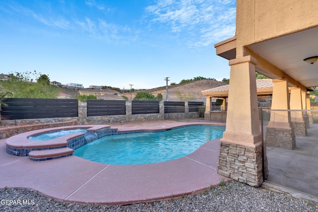 view of pool featuring a patio area, a fenced backyard, and a pool with connected hot tub