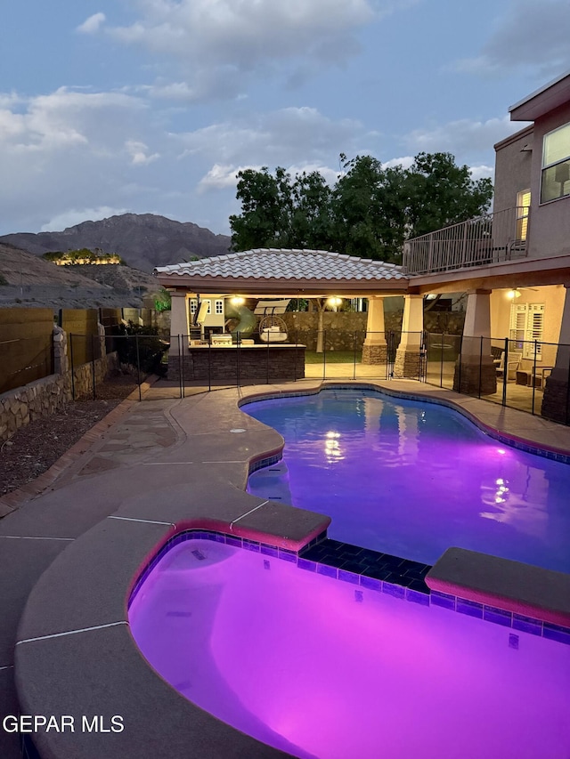 view of pool with fence, a mountain view, a patio area, and a pool with connected hot tub
