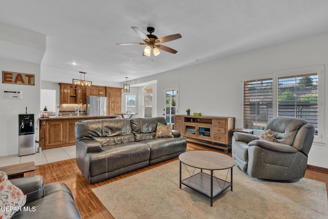 living room featuring ceiling fan, a chandelier, and light wood-type flooring