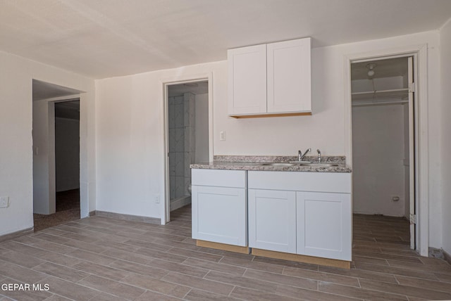 318 Austin St, Fabens, TX 79838 - kitchen featuring wood tiled floors, a sink, and white cabinetry