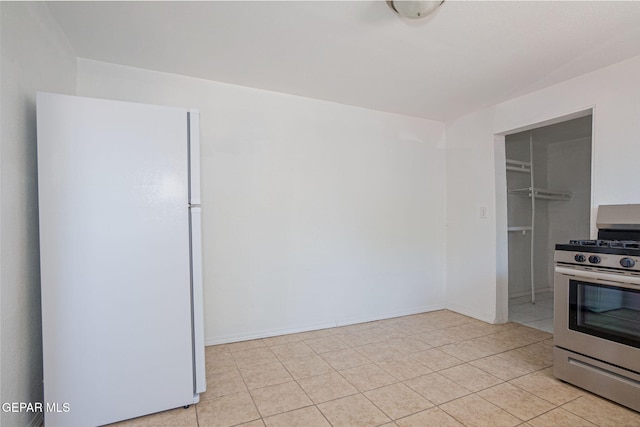 318 Austin St, Fabens, TX 79838 - kitchen featuring freestanding refrigerator, stainless steel gas stove, light tile patterned floors, and baseboards