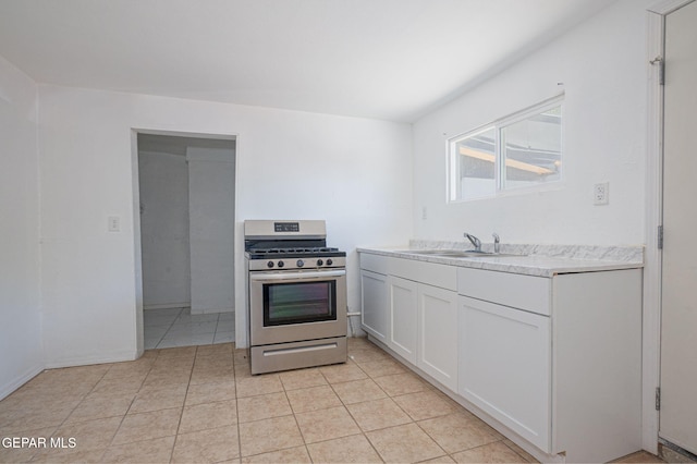 318 Austin St, Fabens, TX 79838 - kitchen featuring stainless steel gas range oven, light countertops, white cabinets, a sink, and light tile patterned floors