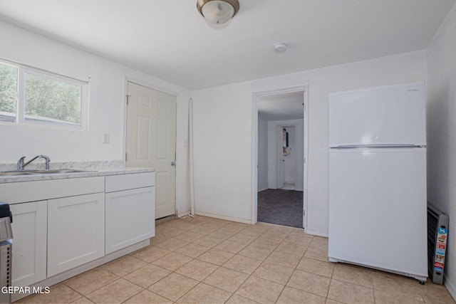 318 Austin St, Fabens, TX 79838 - kitchen with freestanding refrigerator, a sink, light countertops, white cabinetry, and light tile patterned floors