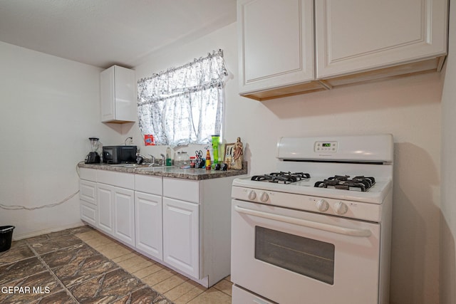 318 Austin St, Fabens, TX 79838 - kitchen with white gas range, white cabinetry, and light stone finish flooring