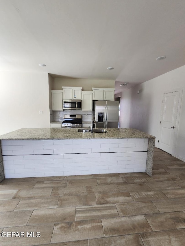 14508 Russell Borea, El Paso, TX 79938 - kitchen featuring appliances with stainless steel finishes, a sink, light stone counters, wood finished floors, and a large island with sink