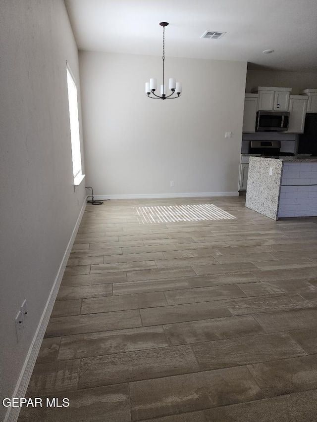 14508 Russell Borea, El Paso, TX 79938 - unfurnished dining area with a chandelier, wood finished floors, and baseboards