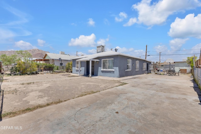 view of front facade featuring fence, concrete driveway, and a patio
