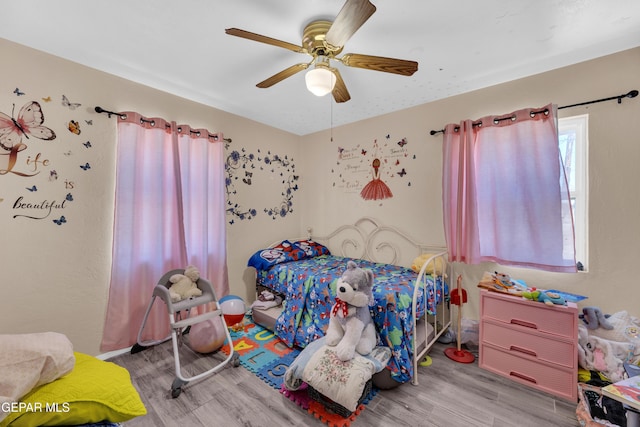 bedroom featuring wood finished floors, a ceiling fan, and baseboards
