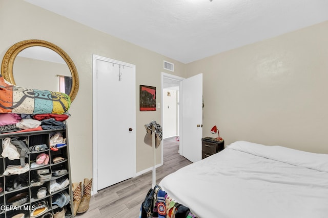 bedroom with light wood-style floors, baseboards, and a closet