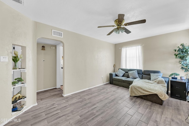 living room with arched walkways, a ceiling fan, wood finished floors, and baseboards