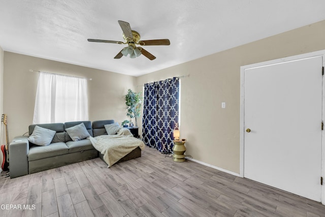 living area featuring wood finished floors, a ceiling fan, and baseboards