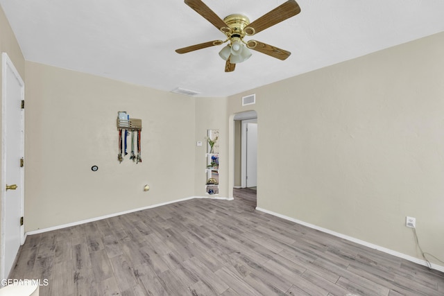 spare room with arched walkways, wood finished floors, ceiling fan, and baseboards