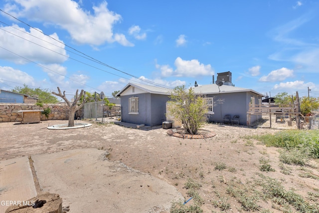 back of property featuring fence and stucco siding