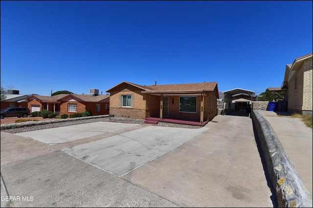 ranch-style home featuring brick siding and a detached carport