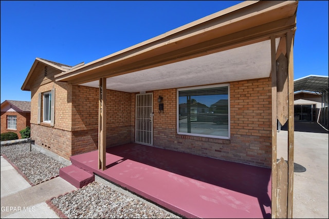 view of front of home featuring brick siding and a patio area