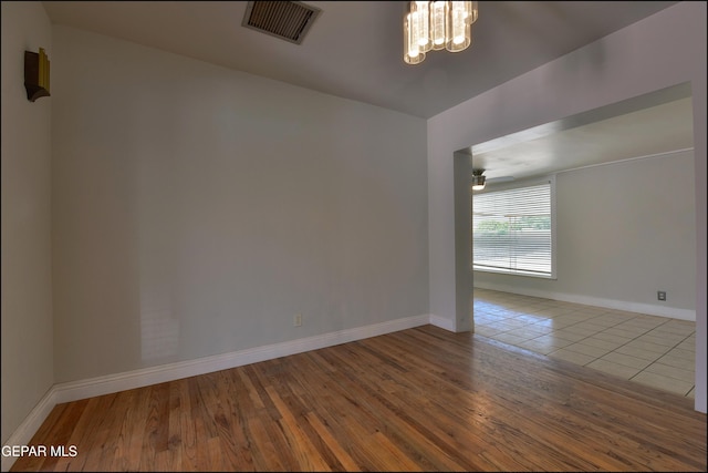 spare room with a chandelier, baseboards, wood finished floors, and ceiling fan