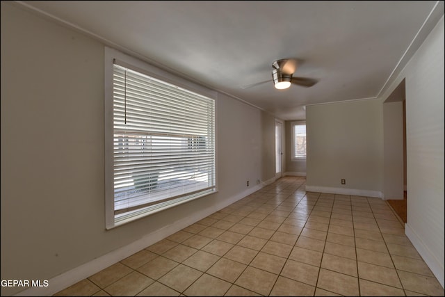 spare room with light tile patterned flooring, ceiling fan, ornamental molding, and baseboards
