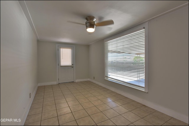 unfurnished room with a ceiling fan, healthy amount of natural light, light tile patterned flooring, and baseboards