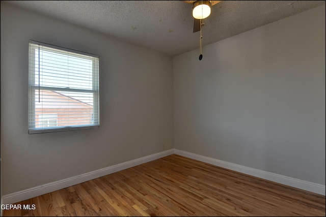 empty room with wood finished floors, baseboards, a textured ceiling, and a ceiling fan