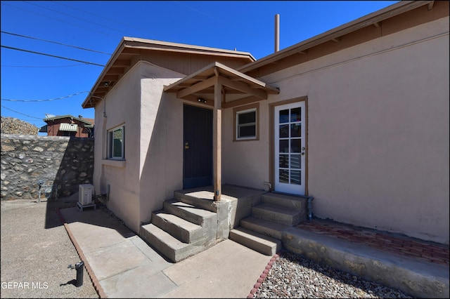 doorway to property with stucco siding and fence
