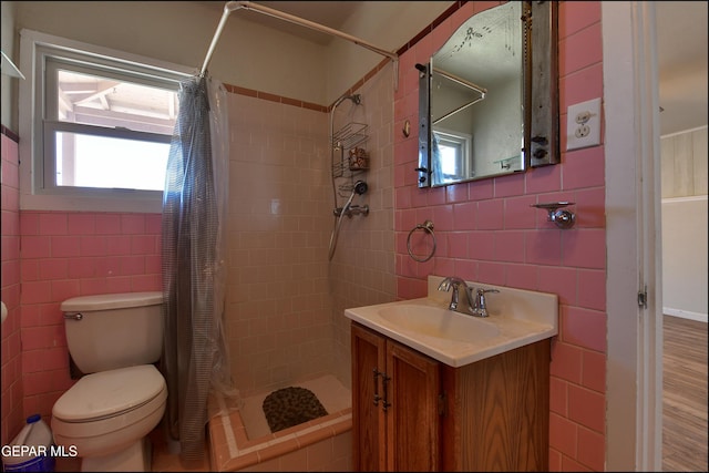 bathroom featuring tile walls, a stall shower, toilet, and vanity