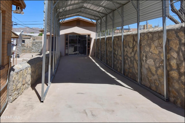 view of parking / parking lot with fence and a carport