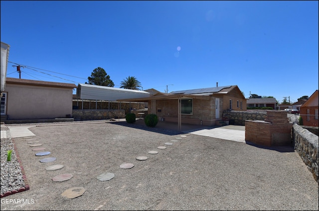 rear view of house featuring solar panels, a patio area, and fence