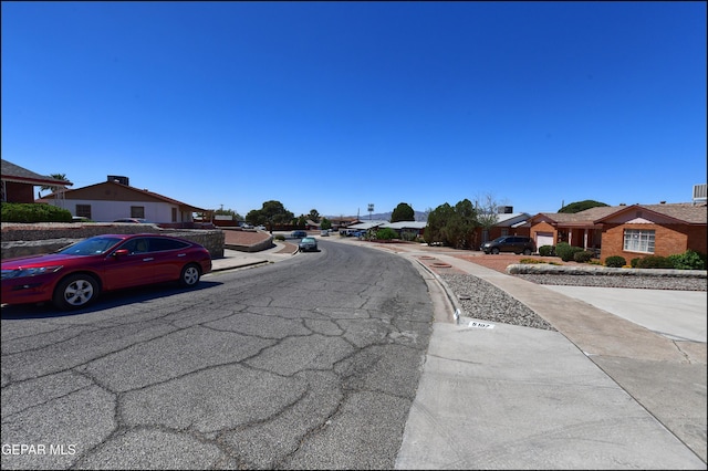view of asphalt street featuring sidewalks, a residential view, and curbs