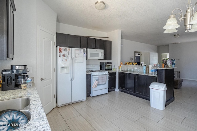kitchen with white appliances, a chandelier, a peninsula, light stone counters, and a textured ceiling