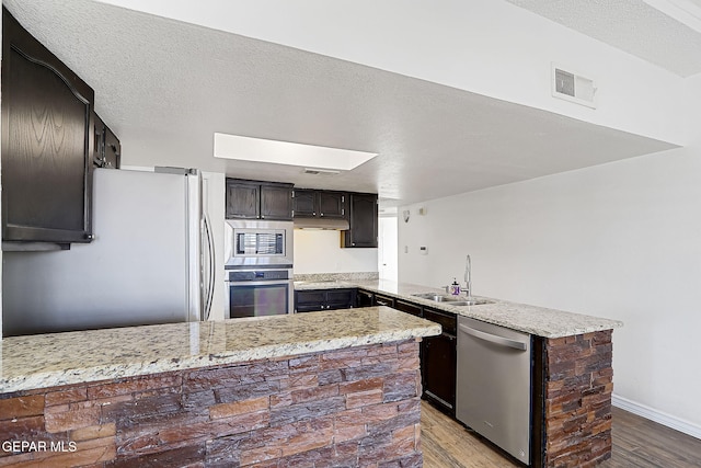 3400 Buffalo Soldier Cir, El Paso, TX 79936 - kitchen featuring appliances with stainless steel finishes, a sink, a peninsula, and wood finished floors