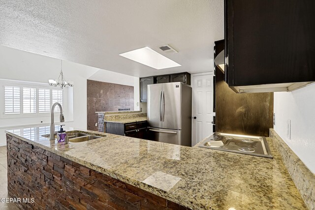 3400 Buffalo Soldier Cir, El Paso, TX 79936 - kitchen with freestanding refrigerator, a sink, electric stovetop, a skylight, and a peninsula