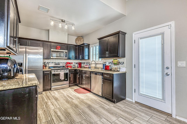 14837 Tierra Crystal Ave, El Paso, TX 79938 - kitchen with appliances with stainless steel finishes, backsplash, dark brown cabinets, light stone countertops, and a sink