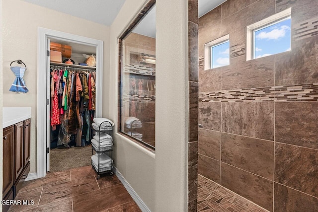 5525 Valley Cedar Dr, El Paso, TX 79932 - bathroom with walk in shower, a spacious closet, vanity, and baseboards