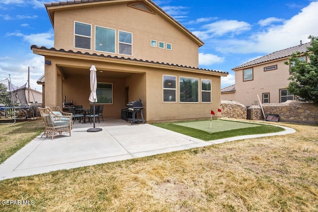 5525 Valley Cedar Dr, El Paso, TX 79932 - back of property featuring a putting area, stucco siding, a patio, and a trampoline