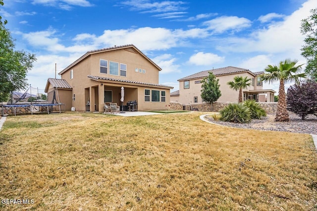 5525 Valley Cedar Dr, El Paso, TX 79932 - back of house with a trampoline, a patio, stucco siding, a tile roof, and a lawn