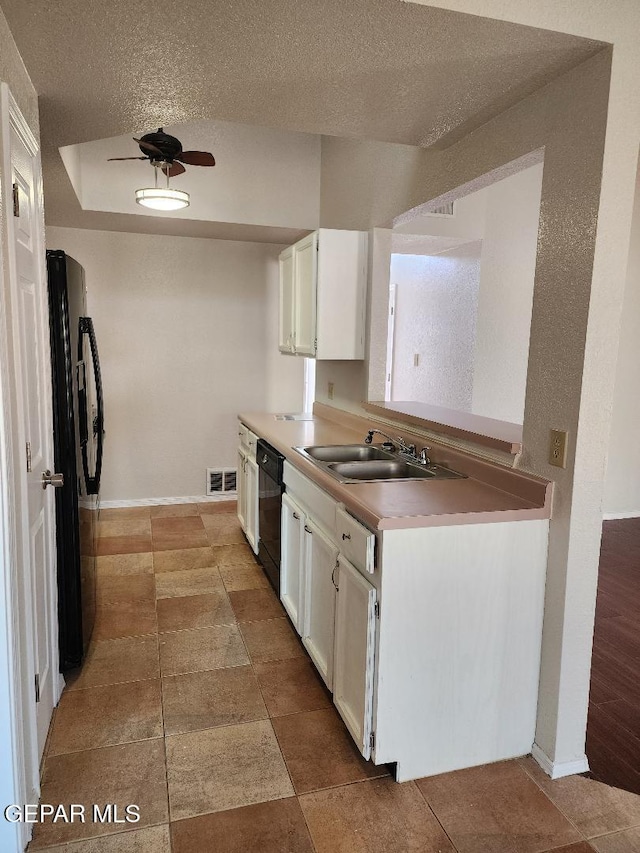 kitchen with black appliances, a sink, a textured ceiling, white cabinets, and light countertops