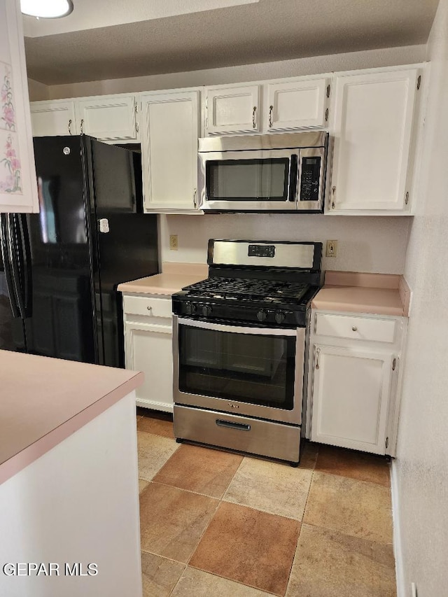 kitchen with stainless steel appliances, light countertops, and white cabinets