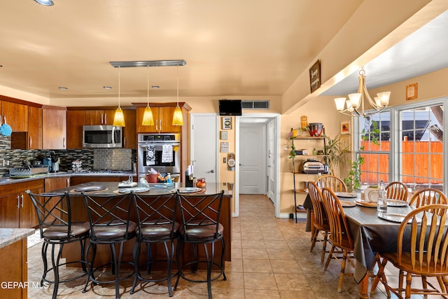 5051 Montoya Dr, El Paso, TX 79922 - kitchen featuring appliances with stainless steel finishes, brown cabinetry, tasteful backsplash, and a chandelier