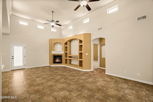 14117 Rainbow Point Dr, El Paso, TX 79938 - unfurnished living room featuring a ceiling fan, a high ceiling, ornamental molding, built in shelves, and a glass covered fireplace