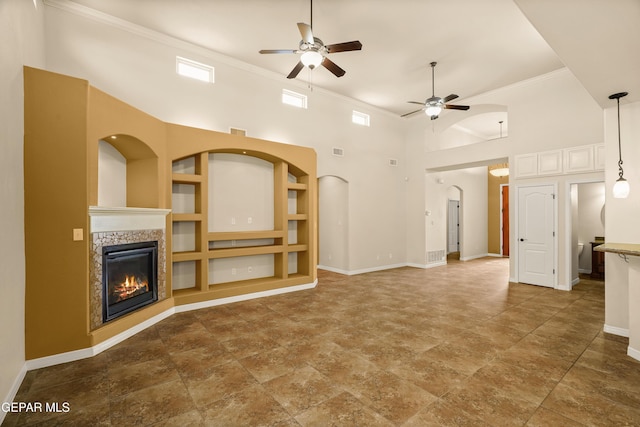 14117 Rainbow Point Dr, El Paso, TX 79938 - unfurnished living room featuring a ceiling fan, a glass covered fireplace, crown molding, a towering ceiling, and arched walkways