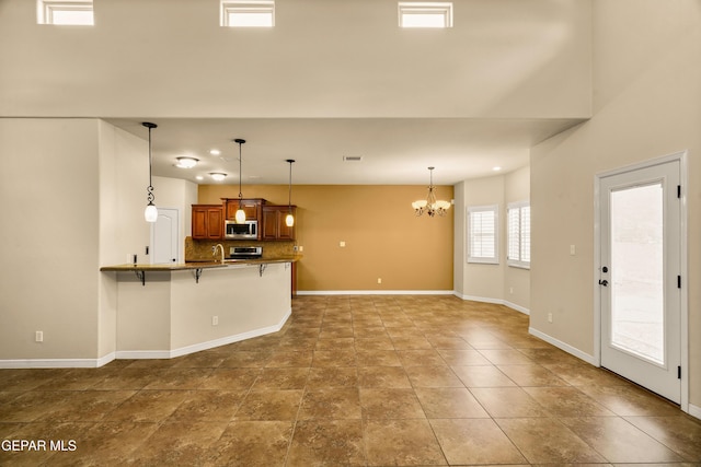 14117 Rainbow Point Dr, El Paso, TX 79938 - kitchen featuring stainless steel appliances, a breakfast bar, brown cabinets, a chandelier, and a peninsula