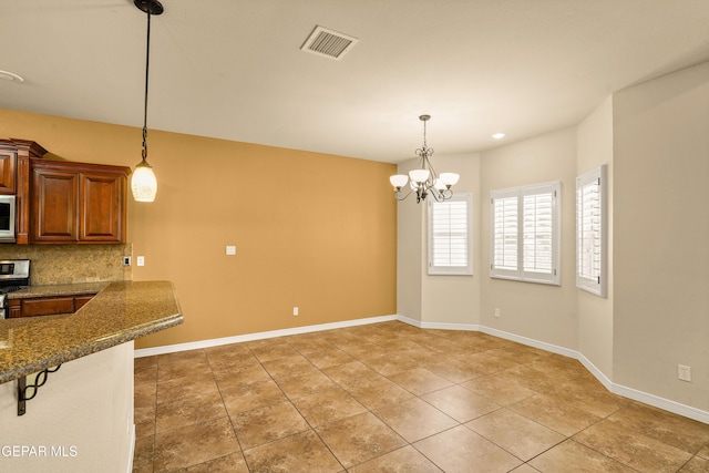 14117 Rainbow Point Dr, El Paso, TX 79938 - kitchen featuring white microwave, stainless steel stove, hanging light fixtures, and decorative backsplash