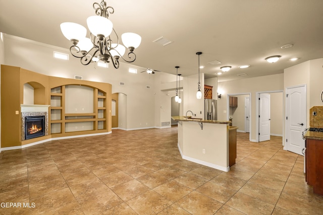 14117 Rainbow Point Dr, El Paso, TX 79938 - kitchen featuring stainless steel fridge, a chandelier, a fireplace, decorative light fixtures, and dark stone countertops