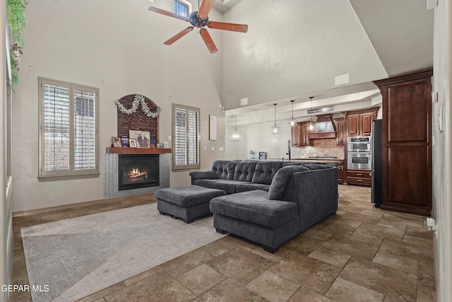 3089 Snowy Point Dr, El Paso, TX 79938 - living area featuring stone tile flooring, ceiling fan, a glass covered fireplace, a high ceiling, and baseboards
