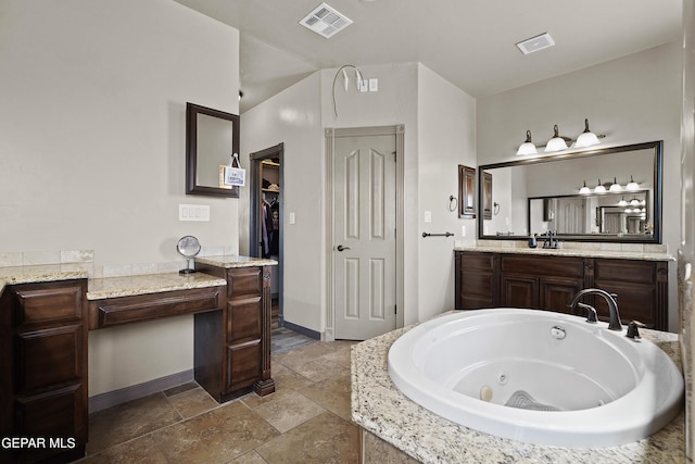 3089 Snowy Point Dr, El Paso, TX 79938 - bathroom featuring baseboards, stone tile floors, a whirlpool tub, vanity, and a spacious closet